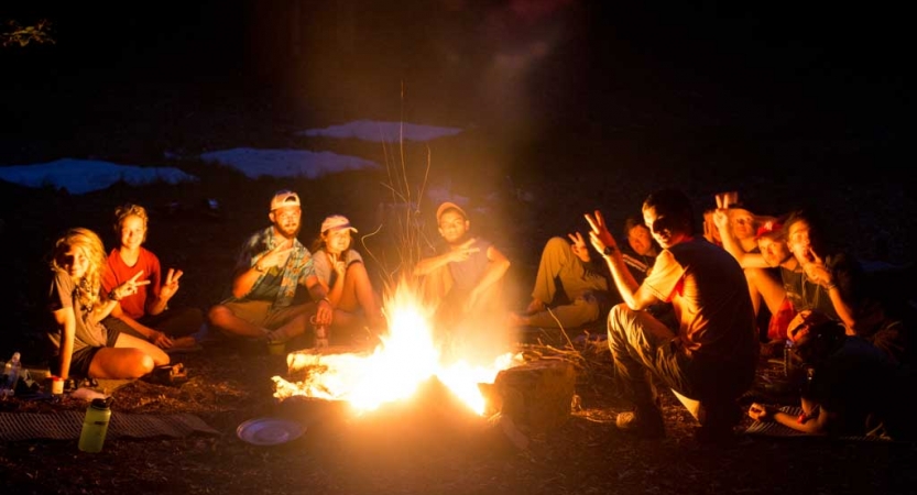 A group of people gather around a campfire